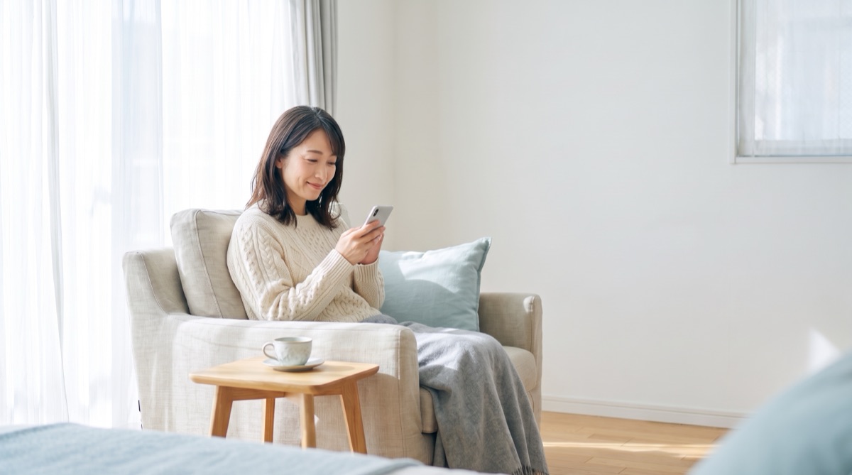 自宅でスマートフォンから相談する女性のイメージ